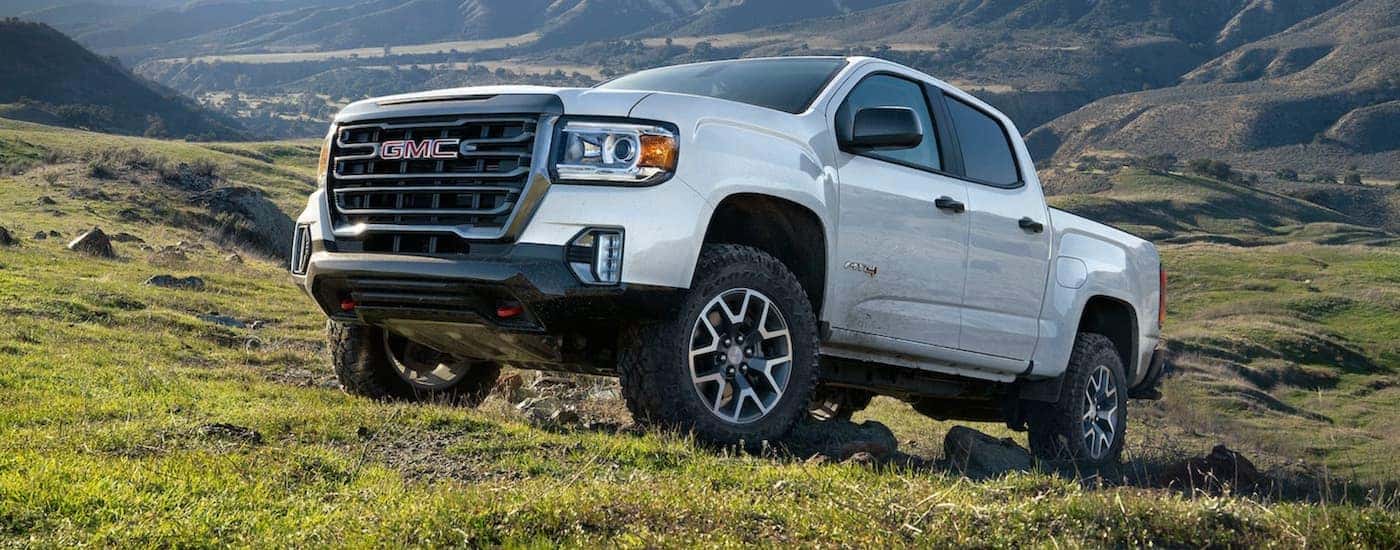 A white 2021 GMC Canyon AT4, a used truck for sale, parked on a grassy hill.
