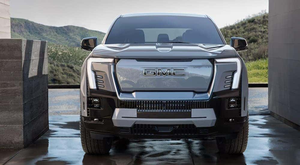 A silver 2025 GMC Sierra EV is shown parked on a wet ground.