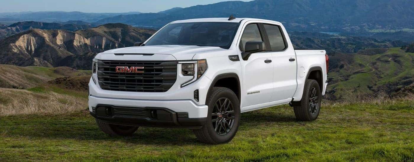 A white 2024 GMC Sierra 1500 Pro parked on a field and angled left.
