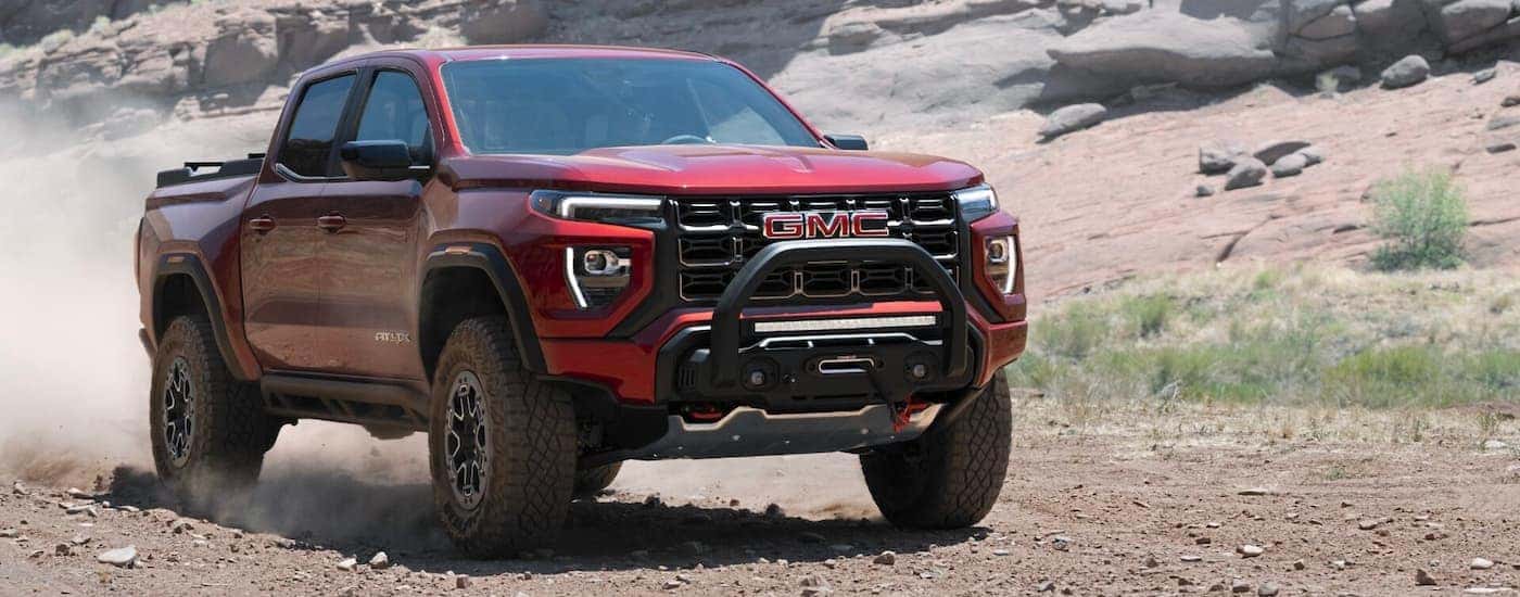 A red 2023 GMC Canyon AT4X driving off-road on a trail.