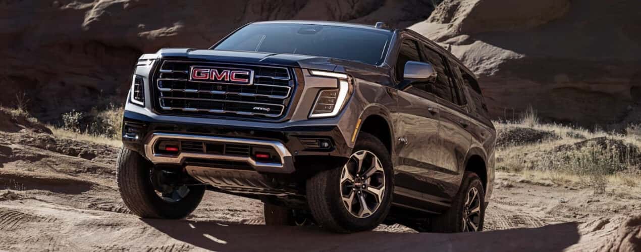 A grey 2025 GMC Yukon AT4 is shown off-road.
