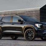 A black 2025 GMC Terrain Elevation parked near a barn.