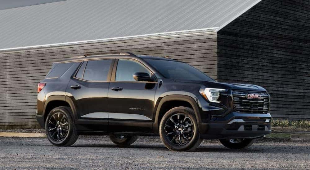 A black 2025 GMC Terrain Elevation parked near a barn.