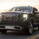 A black 2025 GMC Sierra 1500 Denali driving down a highway