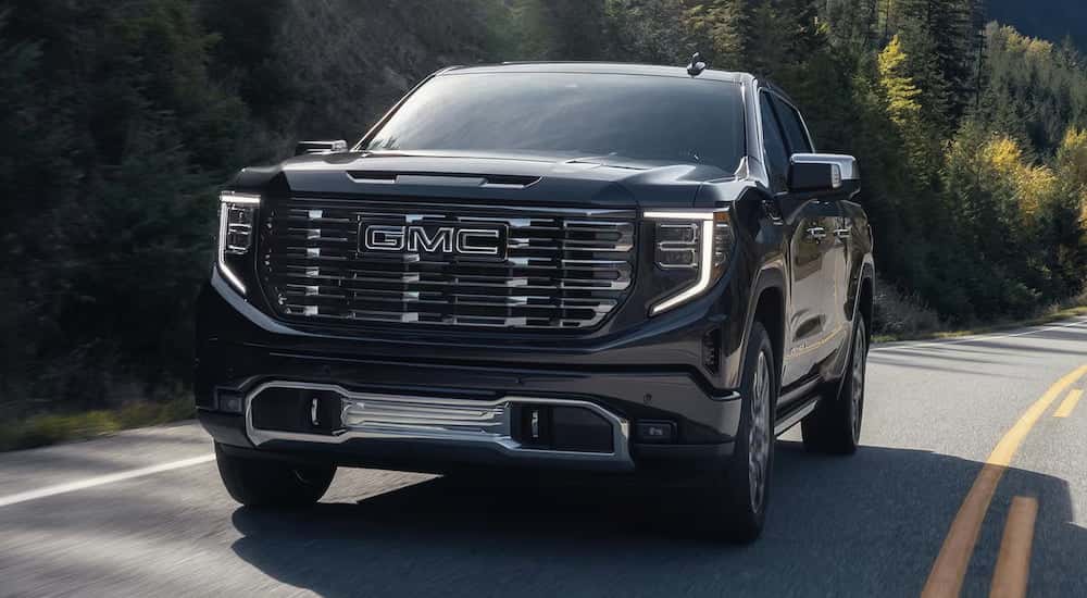 Black 2025 GMC Sierra 1500 Denali Ultimate driving down a road.