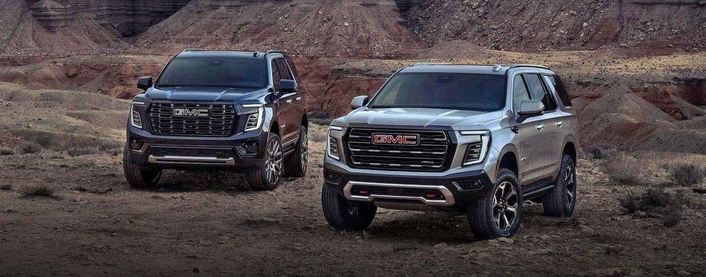 Grey 2025 GMC Yukon and white 2025 GMC Yukon XL for sale in Atlanta parked beside eachother.