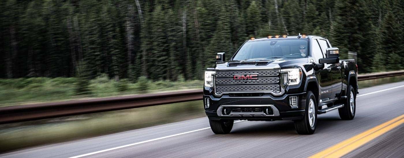A black 2020 GMC Sierra 2500 HD Denali driving on a highway.