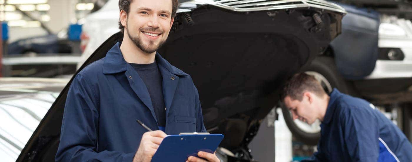 A mechanic is shown holding a clipboard at an auto service center.