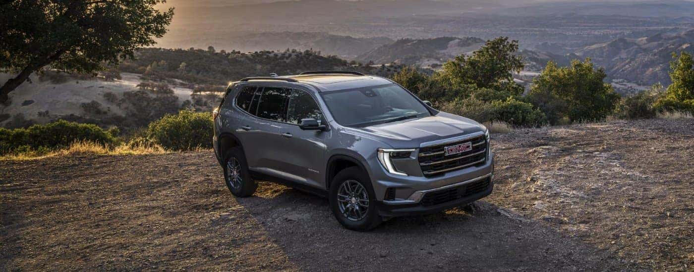 A silver 2025 GMC Acadia Elevation parked off-road from a GMC dealer near me