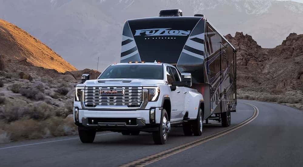 A white 2025 Sierra 2500 HD towing a trailer.