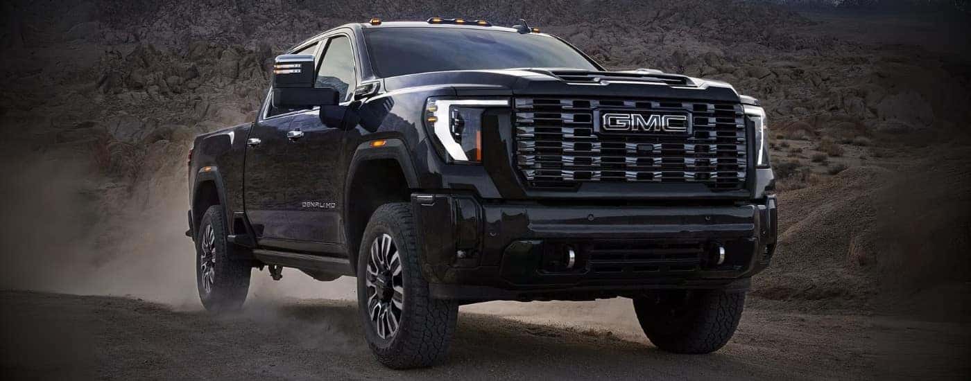 A black 2025 GMC Sierra 2500 HD Denali Ultimate driving off-road.