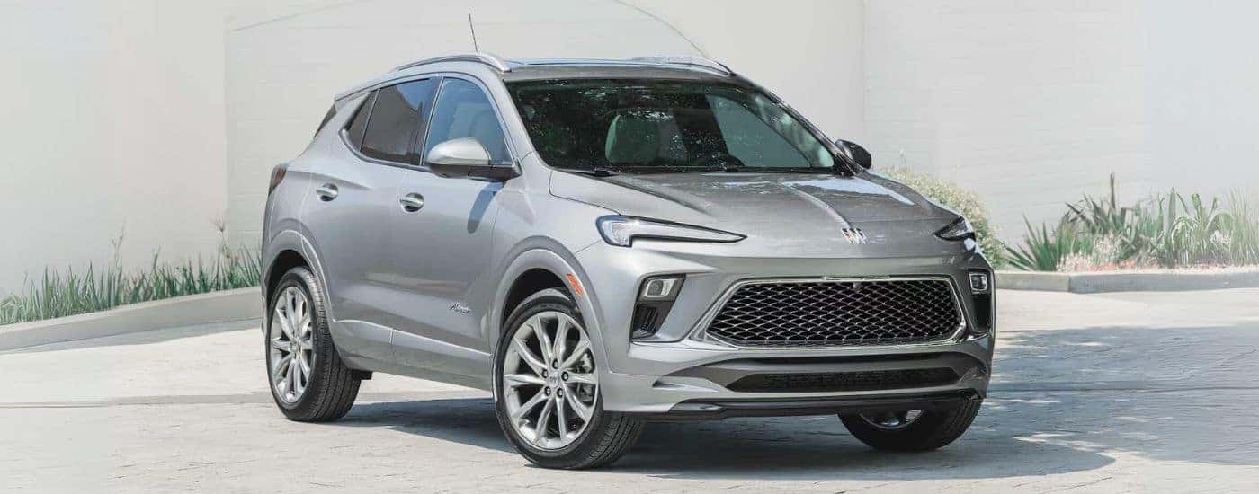 A silver 2025 Buick Encore GX is shown parked near a Buick dealer.