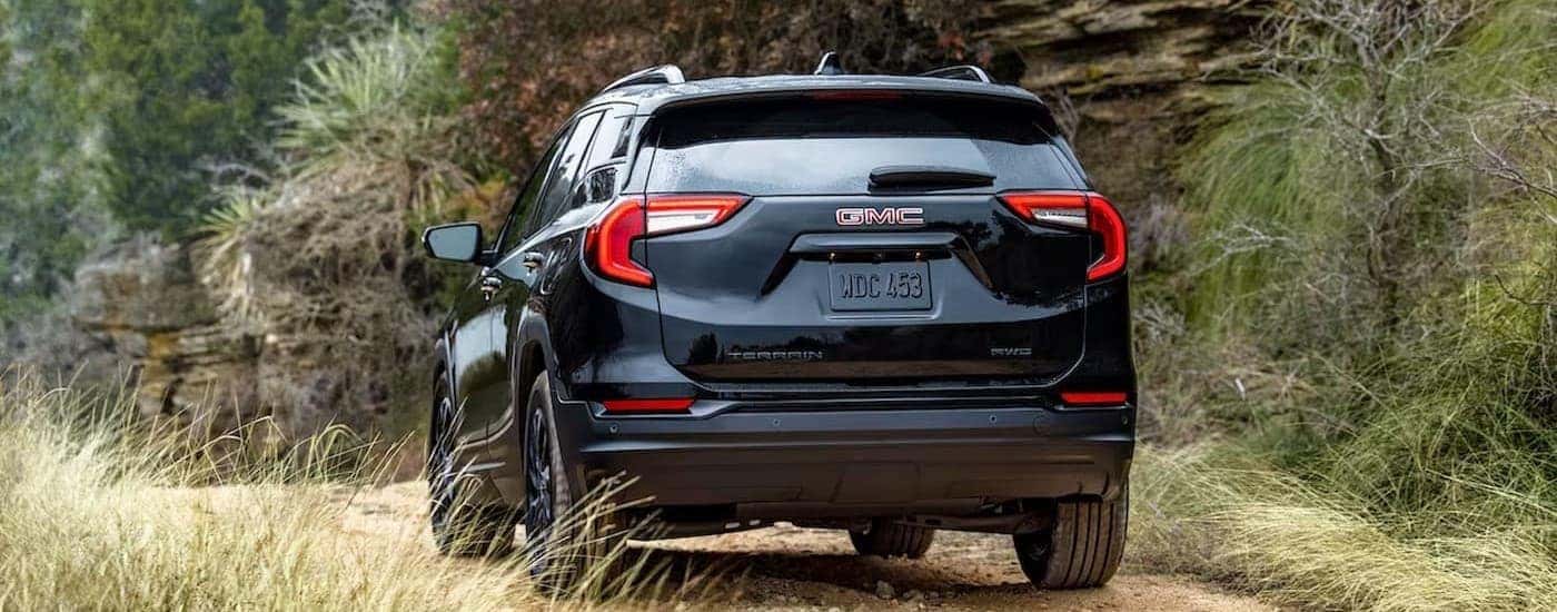 A black 2024 GMC Terrain driving on a dirt road.