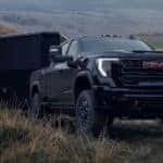 A black 2026 GMC Sierra 2500 HD towing a trailer off-road.