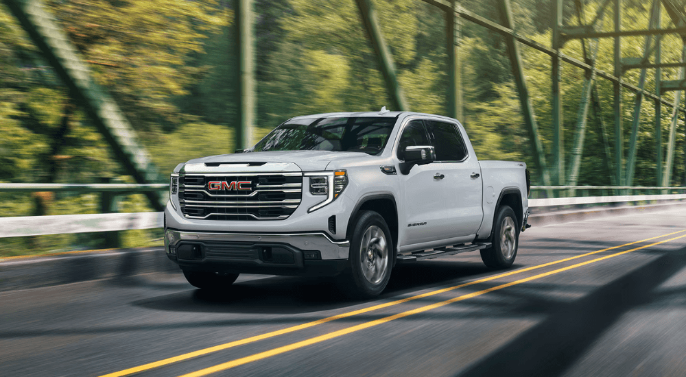 White 2026 GMC Sierra 1500 SLT driving over a bridge