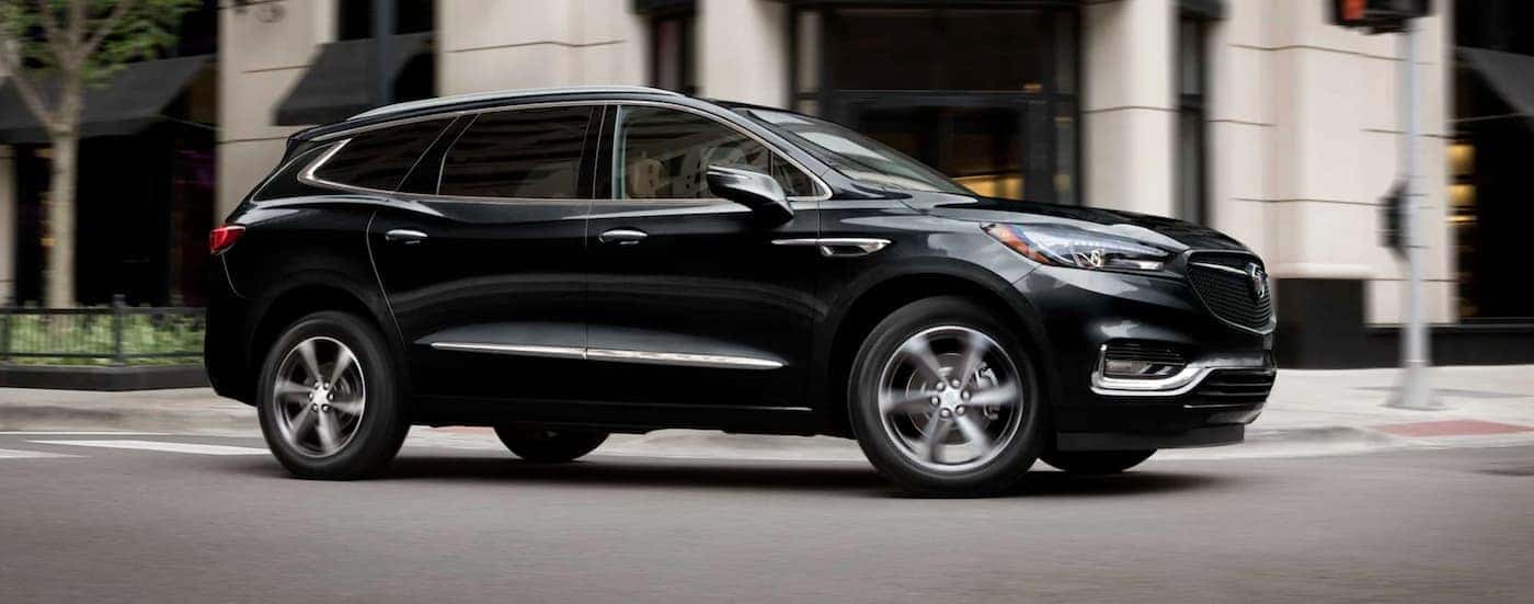 Side of a black 2021 Black Enclave driving down a road.