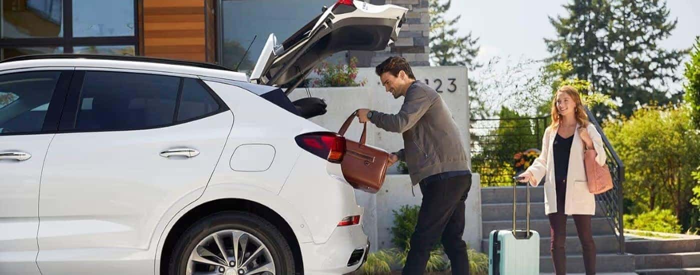 People are shown stowing luggage in a white 2023 Buick Encore GX ST.