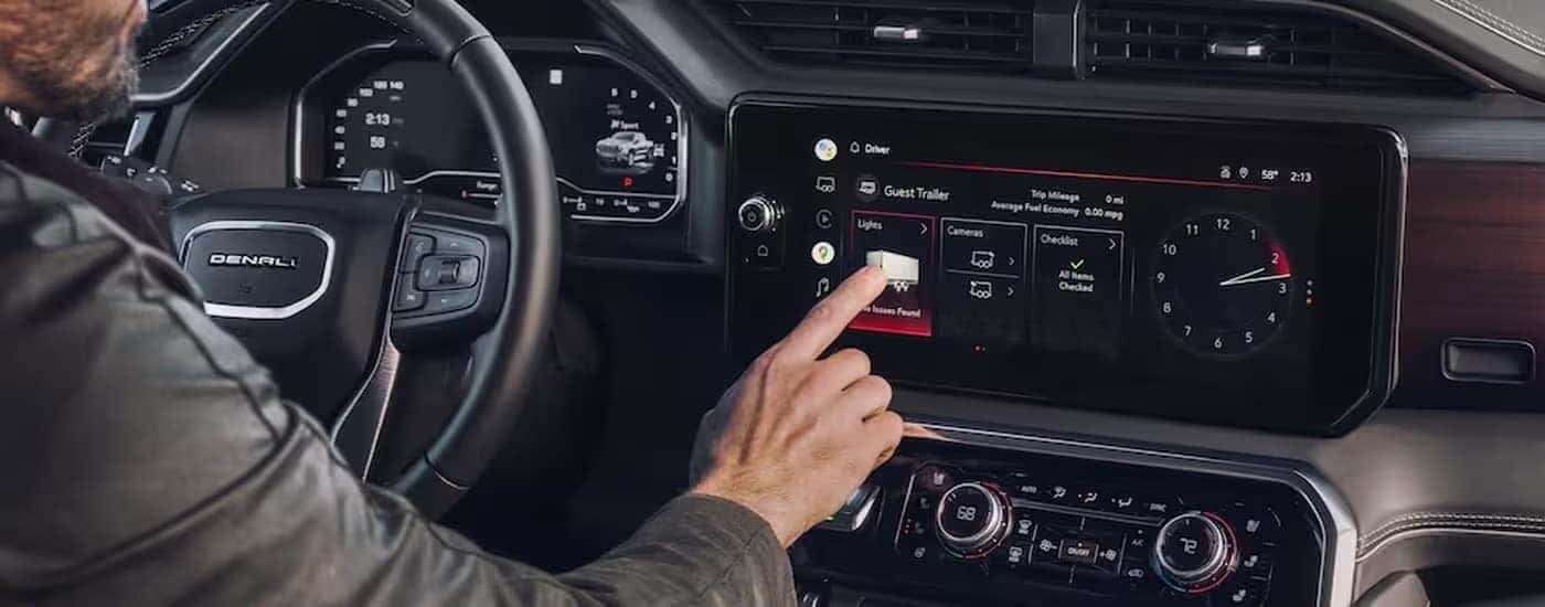 A person is shown using the infotainment screen in a 2023 GMC Sierra 1500 Denali.