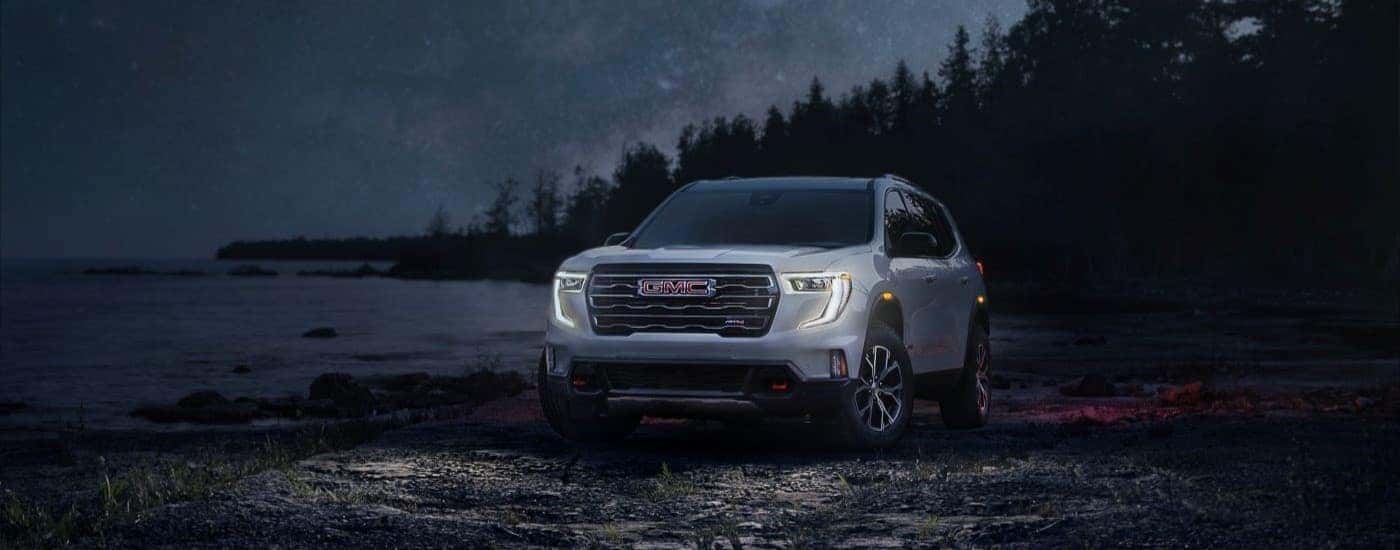 Silver 2024 GMC Acadia AT4 parked off-road at night.