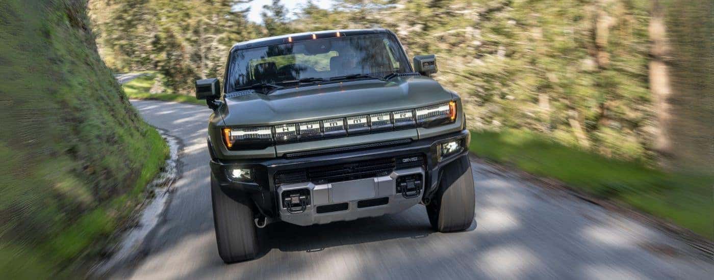 Green 2024 GMC Hummer EV SUV driving on a winding road