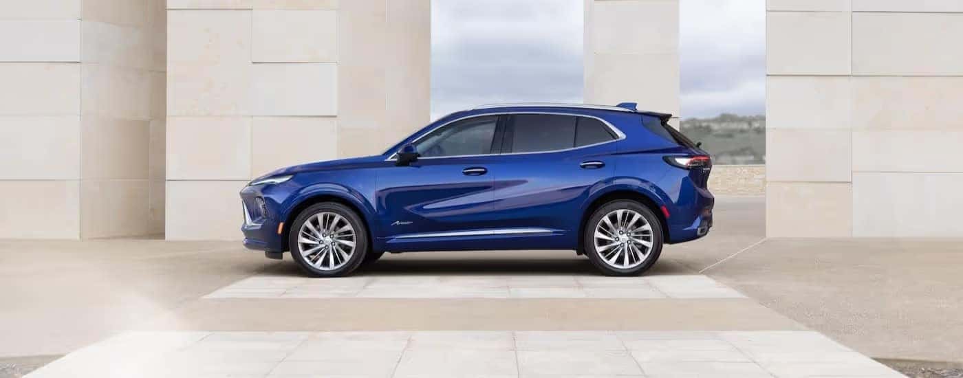 A blue 2025 Buick Envision Avenir is shown parked near stone walls.