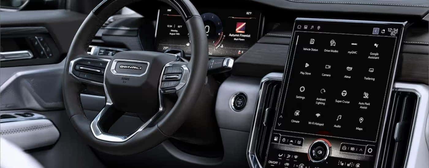 A close up of the infotainment screen and steering wheel in a 2025 GMC Acadia Denali.