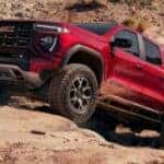 Red 2026 GMC Canyon AT4X driving up rocks