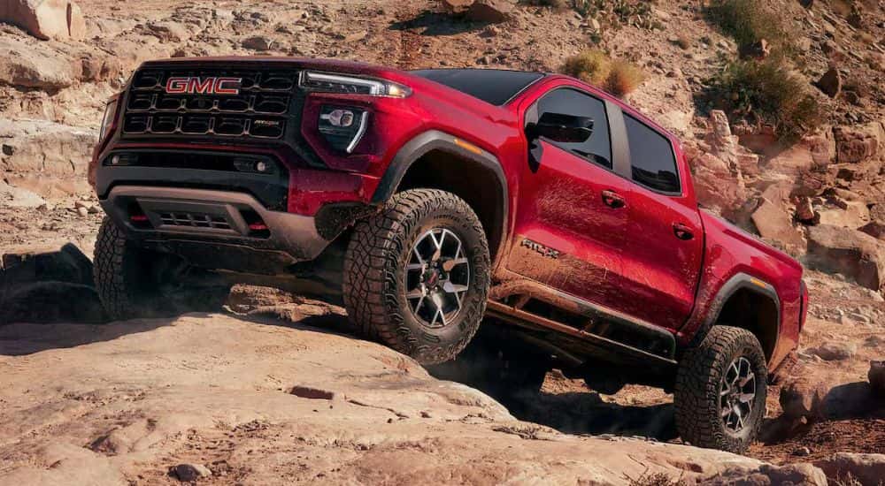 Red 2026 GMC Canyon AT4X driving up rocks