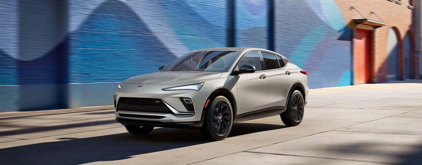 Silver 2026 Buick Envista driving by a brick wall.