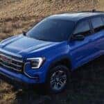 A blue 2026 GMC Terrain parked in a field at an angle.
