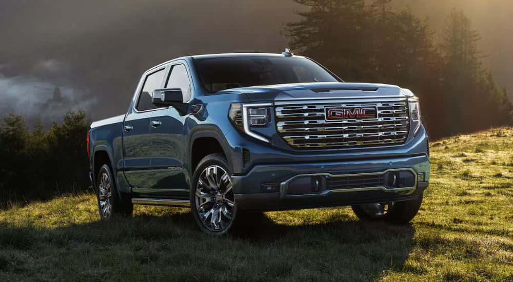 Blue 2026 GMC Sierra 1500 parked in a green valley at sunrise