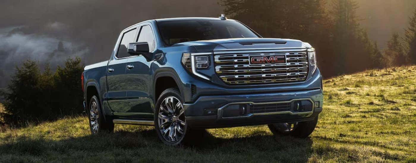 A blue 2025 GMC Sierra 1500 Denali driving on a field.