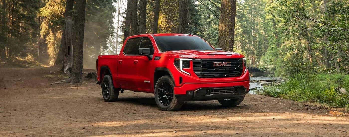 A red 2026 GMC Sierra 1500 parked in a forest.