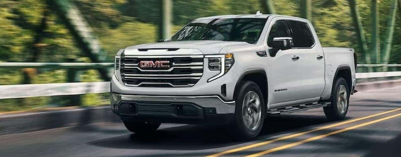 A white 2024 GMC Sierra 1500 driving on a bridge.