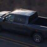 Aerial view of a black 2027 GMC Sierra 1500 driving on a highway.