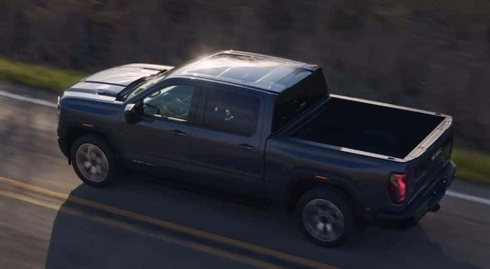 Aerial view of a black 2027 GMC Sierra 1500 driving on a highway.