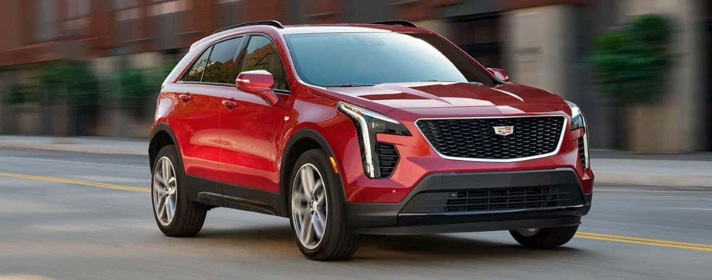 A red 2023 Cadillac XT4 is shown driving on a city street.
