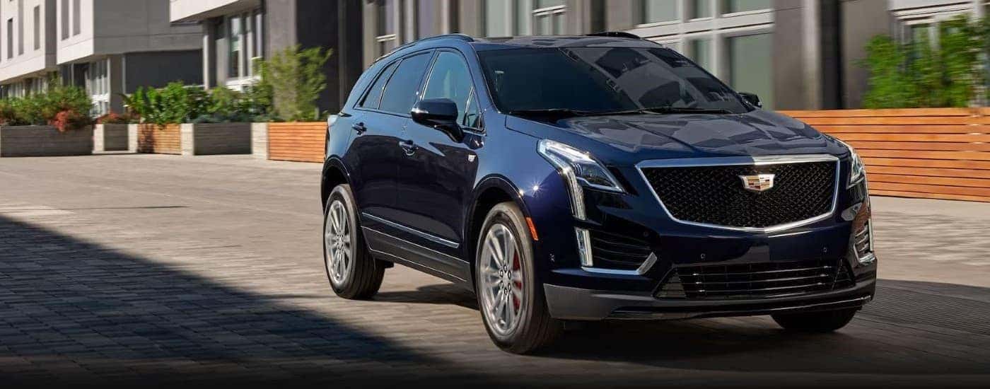 A dark blue 2023 Cadillac XT5 is shown driving on a city street.