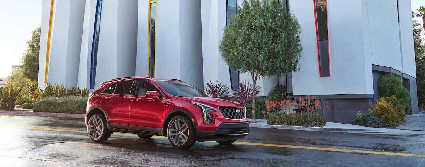 A red 2023 Cadillac XT4 is shown driving on a city street after a rainstorm.
