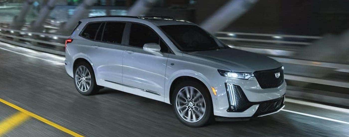 A white 2023 Cadillac XT6 is shown from the side on a street at night.