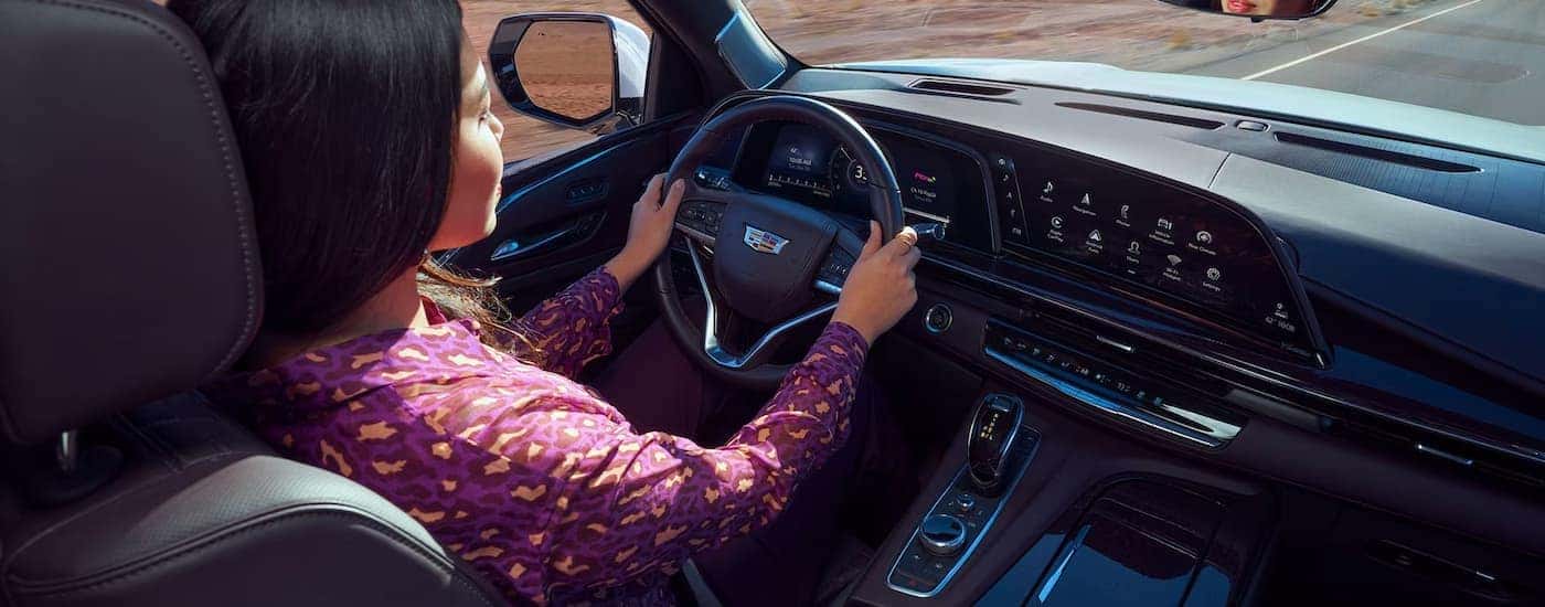 A woman is shown driving a 2023 Cadillac Escalade.