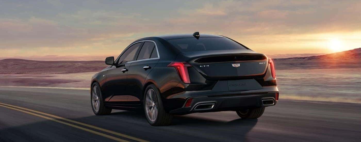 A black 2023 Cadillac CT4 Sport is shown on an open road at dusk.