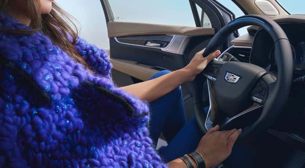 A person in a purple coat is shown in a 2024 Cadillac XT6.