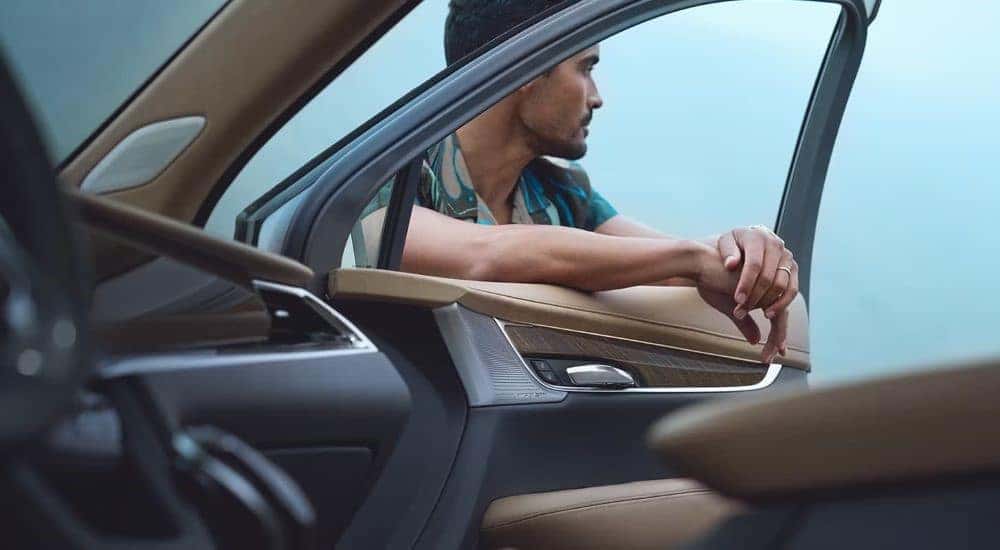 A person is shown leaning against a 2024 Cadillac XT6 at a Cadillac dealer.