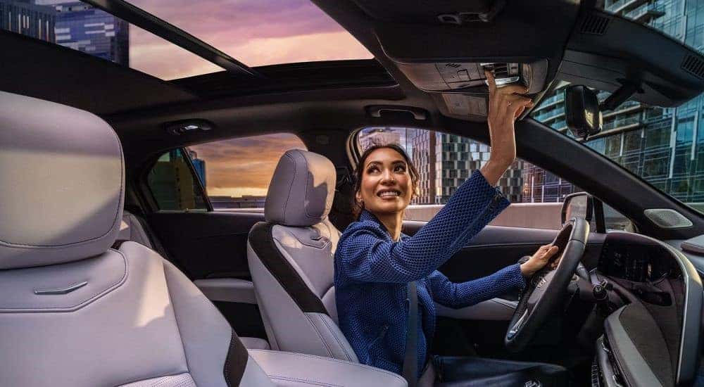 A person is shown opening the moonroof in a 2024 Cadillac XT4.