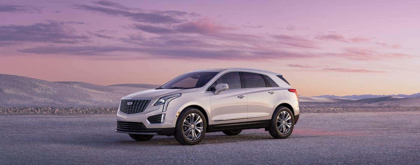 A white 2023 Cadillac XT5 is shown from the side while parked off-road.