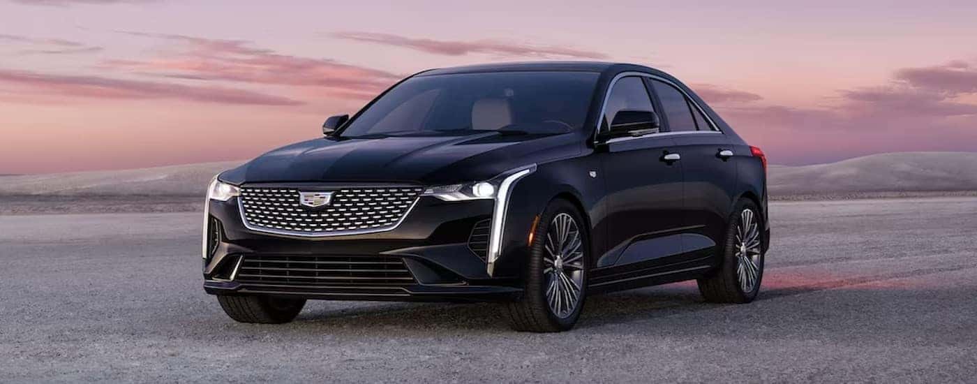 A black 2024 Cadillac CT4 is shown parked off-road.
