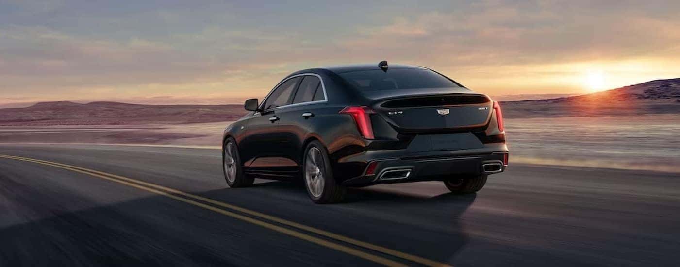 A black 2024 Cadillac CT4 is shown driving on a highway.