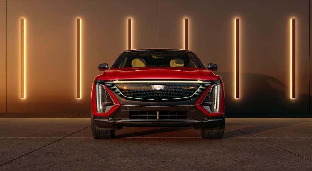 A red 2024 Cadillac LYRIQ is shown parked near several lights on a wall.