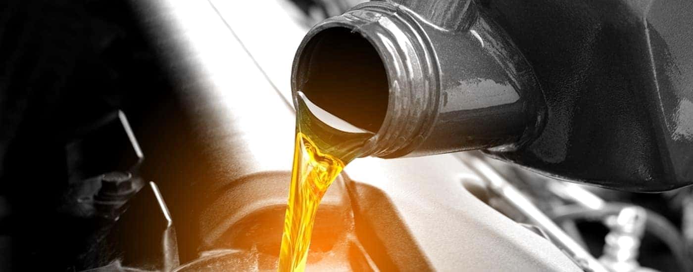 A close-up of oil being poured into an engine is shown.